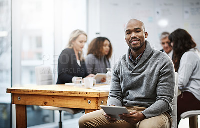 Buy stock photo Portrait of a young businessman using a digital tablet in an office with his colleagues in the background