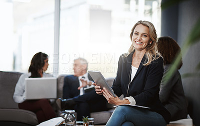 Buy stock photo Portrait of a mature businesswoman using a digital tablet in an office with her colleagues in the background