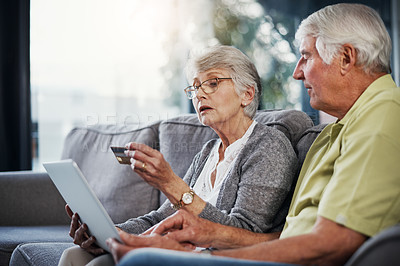 Buy stock photo Shot of a senior couple using a digital tablet and credit card on the sofa at home