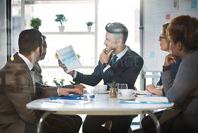 Buy stock photo Cropped shot of a handsome young businessman showing his colleagues something on a tablet during a meeting in the boardroom