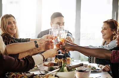 Buy stock photo Shot of a group of young friends making a toast at a dinner party