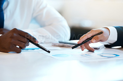 Buy stock photo Closeup of two unrecognizable businesspeople making notes while looking at graphs in the office at work during the day