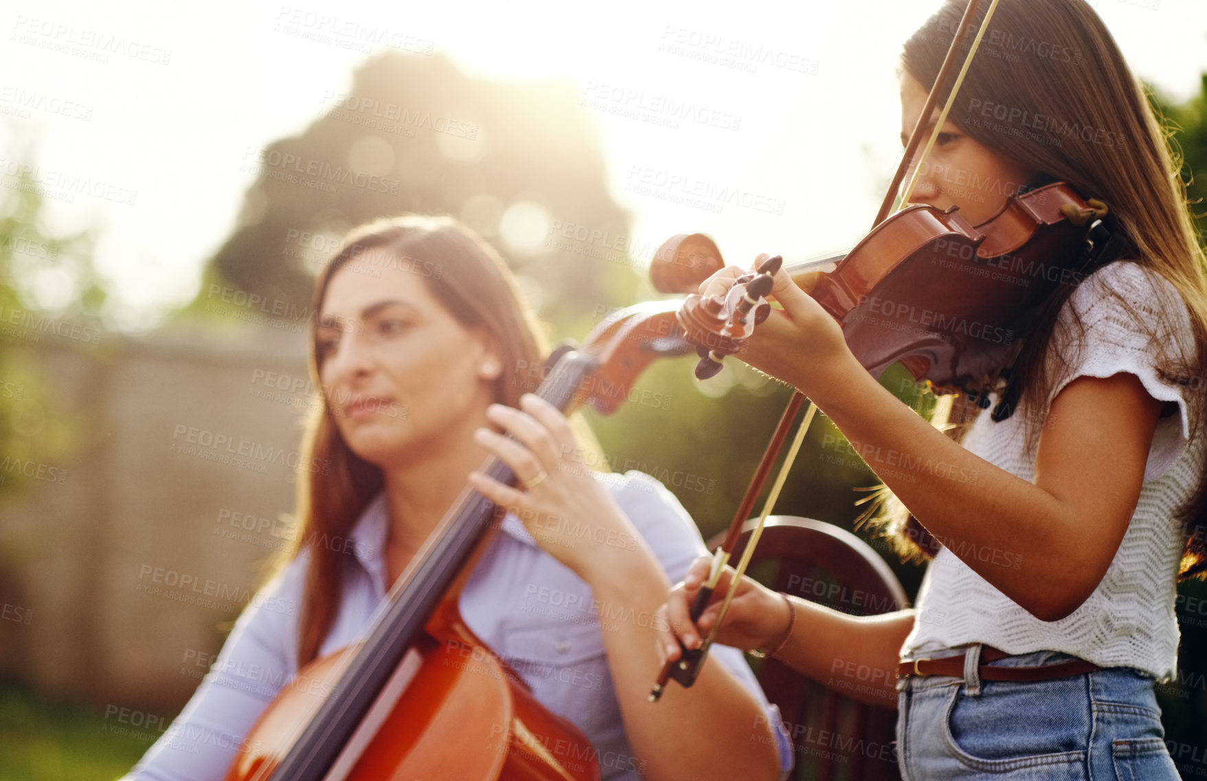 Buy stock photo Cropped shot of a mother and daughter playing musical instruments together in the backyard