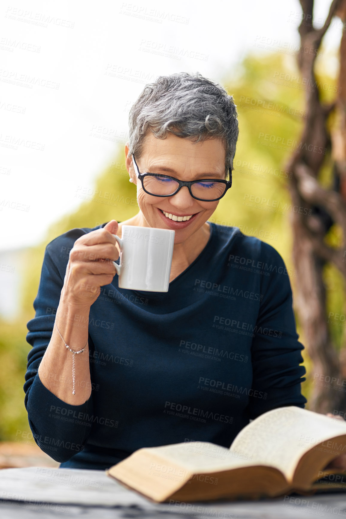 Buy stock photo Cropped shot of an attractive senior woman reading her bible while drinking coffee outside