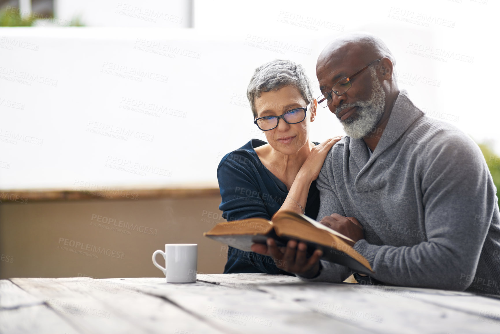 Buy stock photo Cropped shot of an affectionate senior couple reading their bible while sitting outside