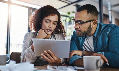 Buy stock photo Shot of a young couple using a digital tablet while planning their budget together at home