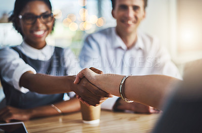 Buy stock photo Cropped shot of two young businesspeople shaking hands during a meeting in the boardroom