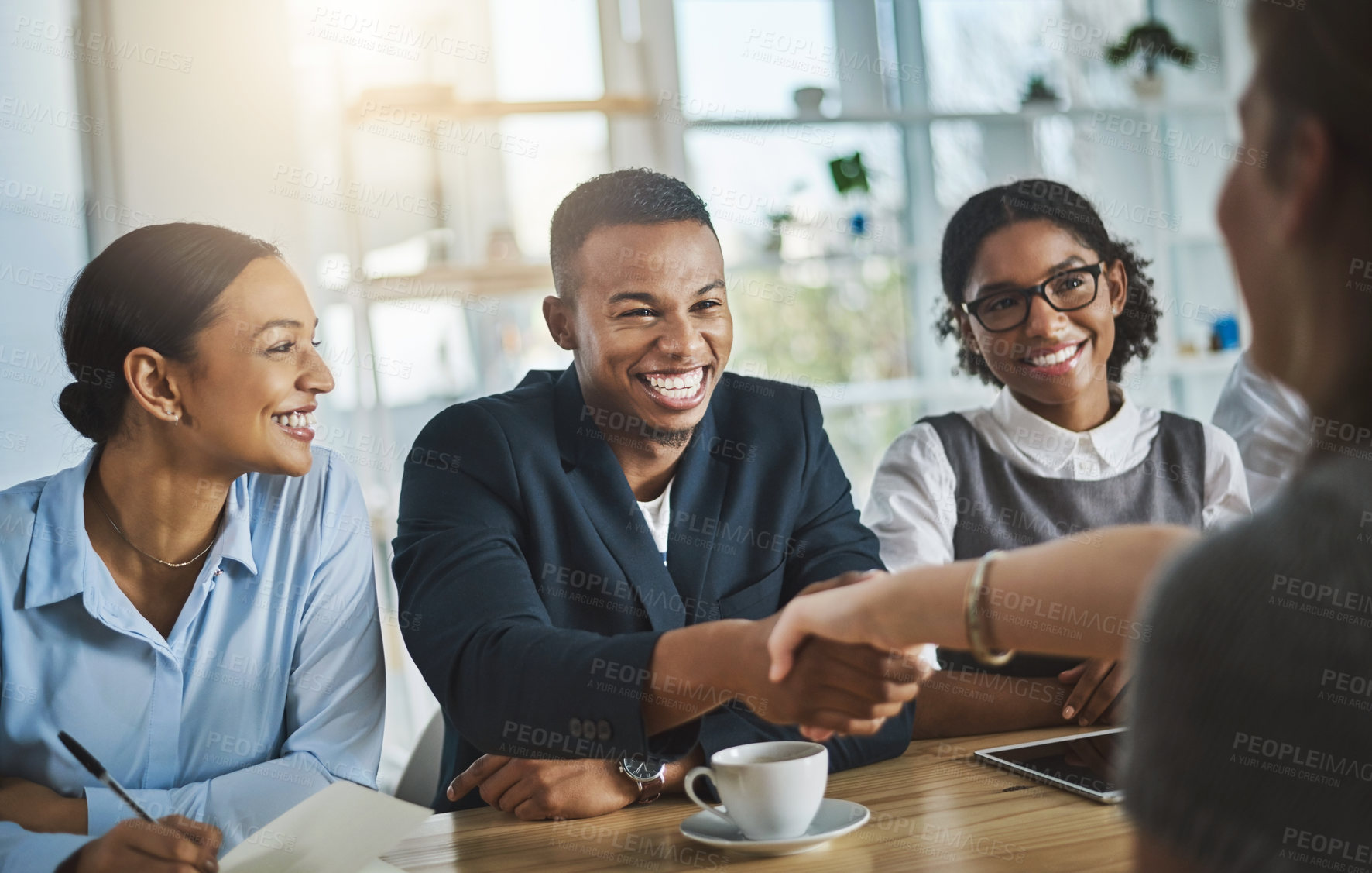 Buy stock photo Cropped shot of two young businesspeople shaking hands during a meeting in the boardroom