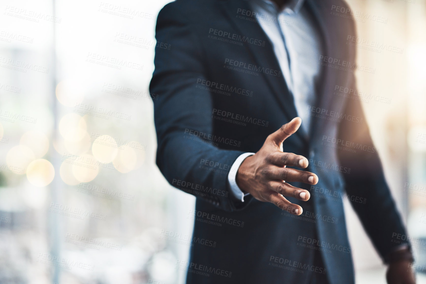 Buy stock photo Cropped shot of an unrecognizable young businessman offering his hand while standing in his modern office
