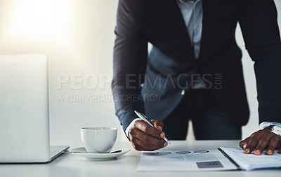 Buy stock photo Cropped shot of an unrecognizable young businessman taking notes while working in his modern office