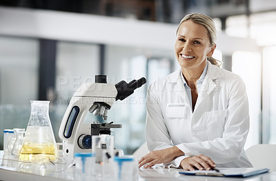 Buy stock photo Cropped portrait of an attractive mature female scientist using a microscope while doing research in her lab