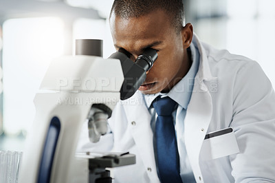 Buy stock photo Cropped portrait of a handsome young male scientist using a microscope while doing research in his lab