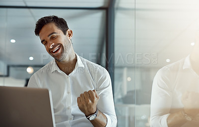 Buy stock photo Cropped shot of a handsome young businessman cheering while working on his laptop in the office
