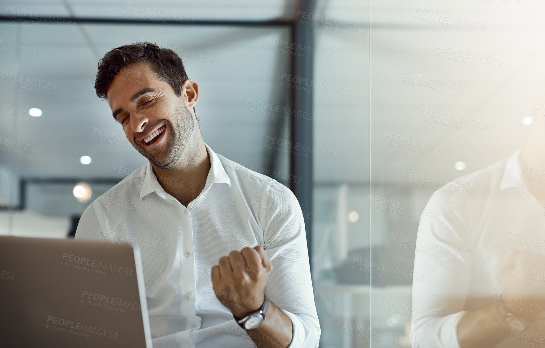 Buy stock photo Cropped shot of a handsome young businessman cheering while working on his laptop in the office