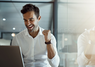 Buy stock photo Cropped shot of a handsome young businessman cheering while working on his laptop in the office