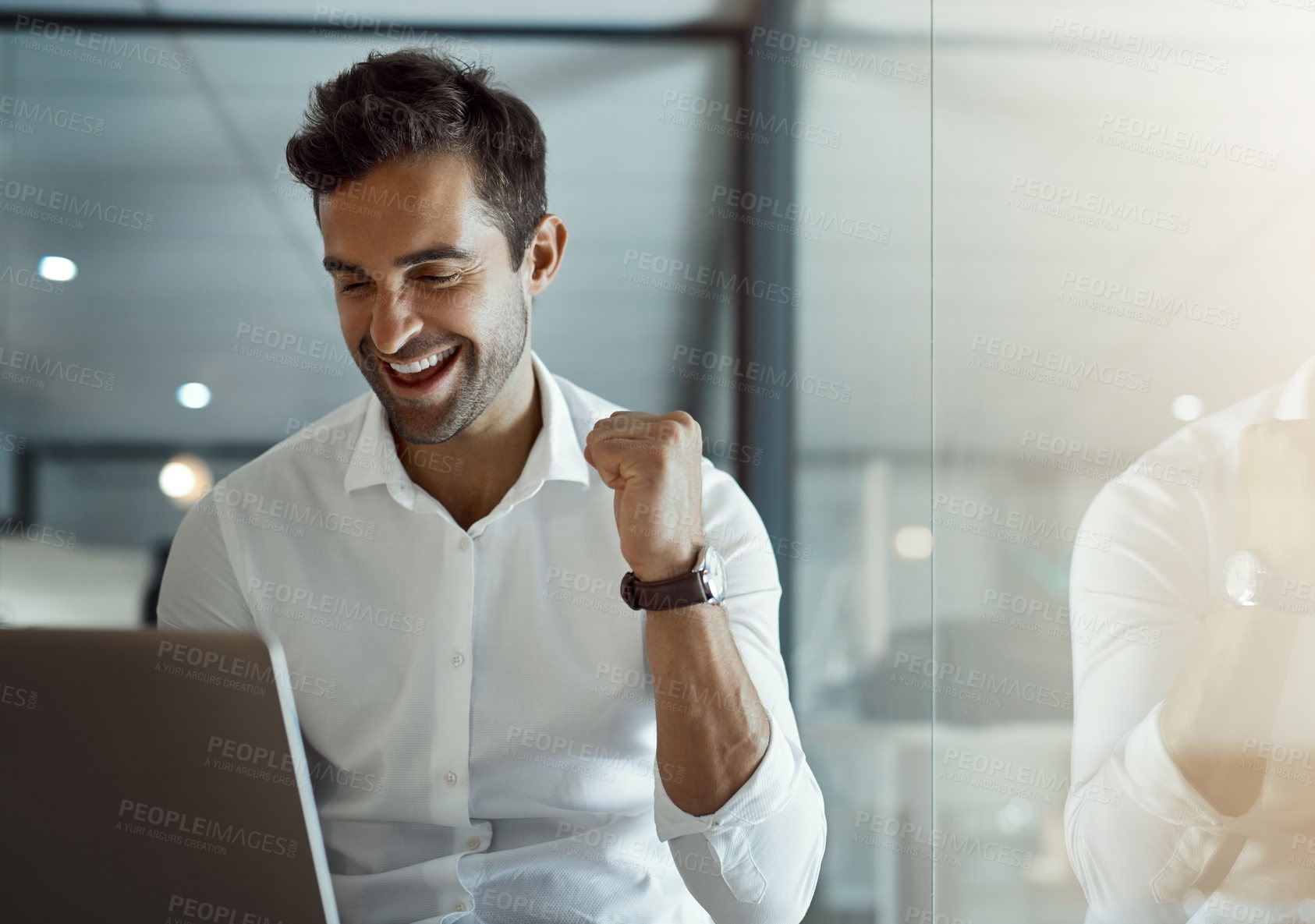 Buy stock photo Cropped shot of a handsome young businessman cheering while working on his laptop in the office