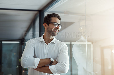 Buy stock photo Cropped shot of a handsome young businessman looking thoughtful while standing with his arms folded in the office