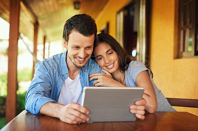Buy stock photo Shot of a young couple using a digital tablet together outdoors