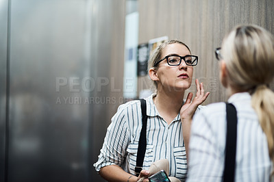 Buy stock photo Shot of a carefree young businesswoman looking at her reflection in the mirror at work during the day
