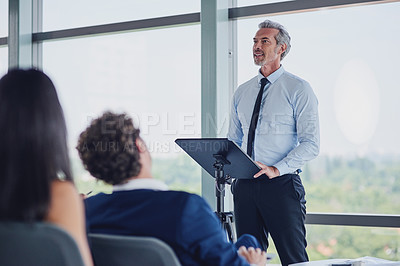 Buy stock photo Low angle shot of a handsome mature male speaker addressing a group of businesspeople during a seminar in the conference room