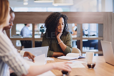 Buy stock photo Cropped shot of an attractive young businesswoman looking over some notes during a meeting in the boardroom