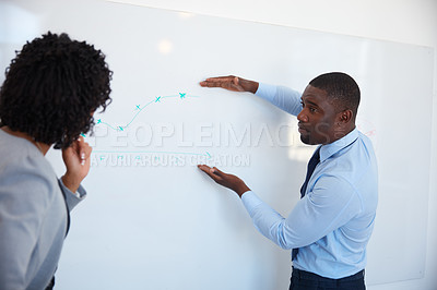 Buy stock photo Cropped shot of a young businessman explaining information on a whiteboard to his female colleague in the office