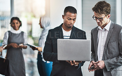 Buy stock photo Shot of a group of young cheerful businesspeople browsing on digital devices while working together in the office at work