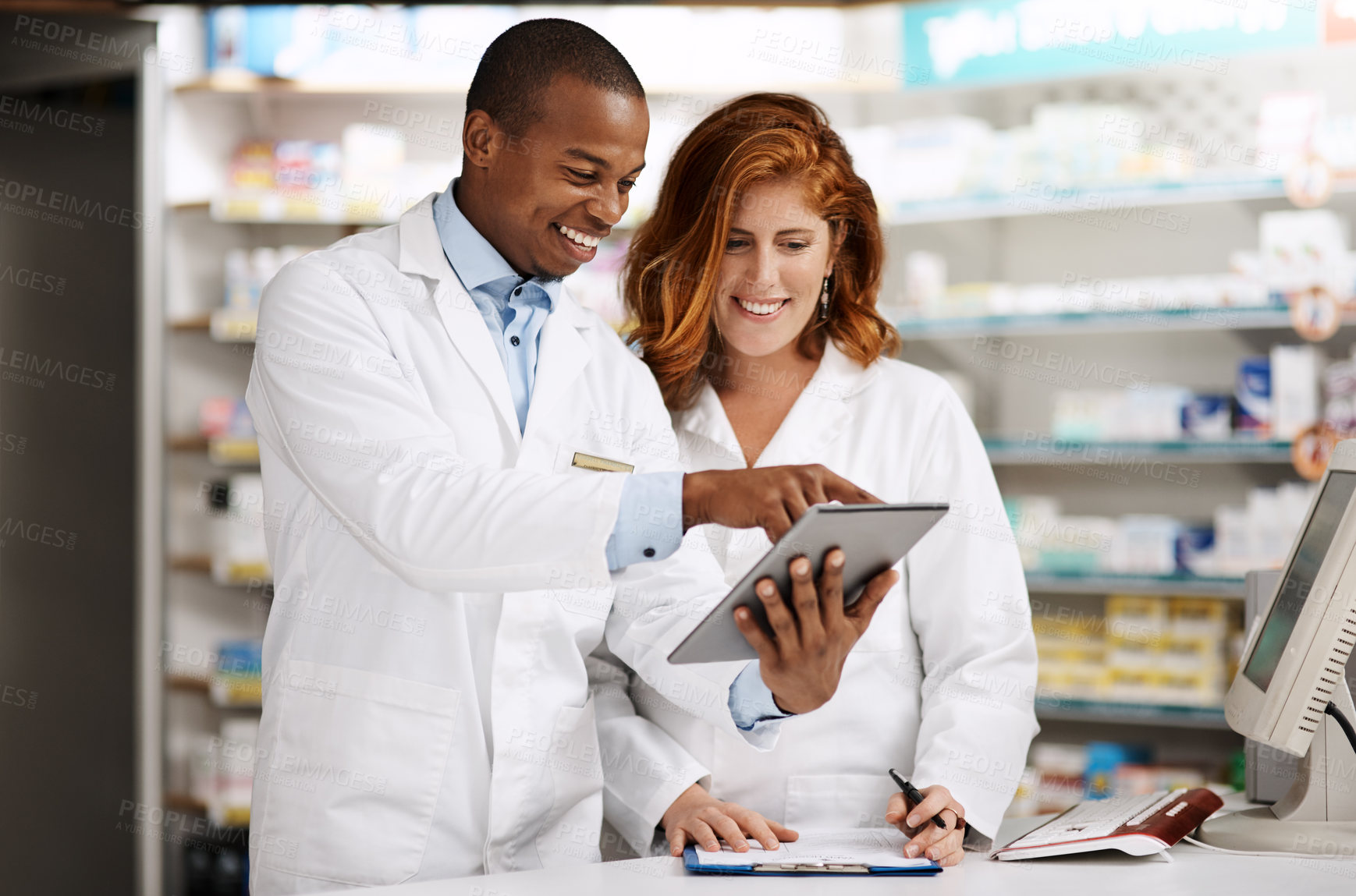 Buy stock photo Shot of two pharmacists working together on a digital tablet in a chemist