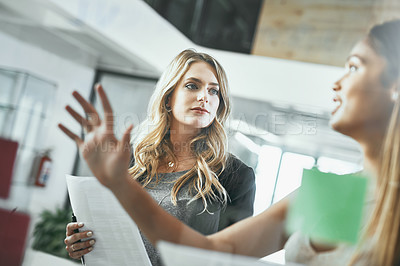Buy stock photo Shot of two young businesswomen brainstorming in a modern office