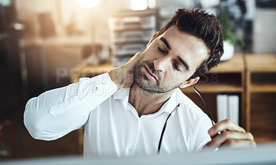 Buy stock photo Shot of a young businessman suffering with neck pain while working in an office