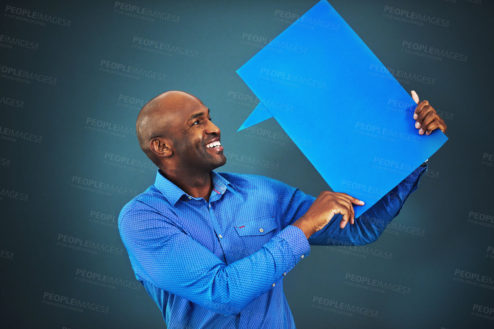 Buy stock photo Studio shot of a man holding a speech bubble against a blue background
