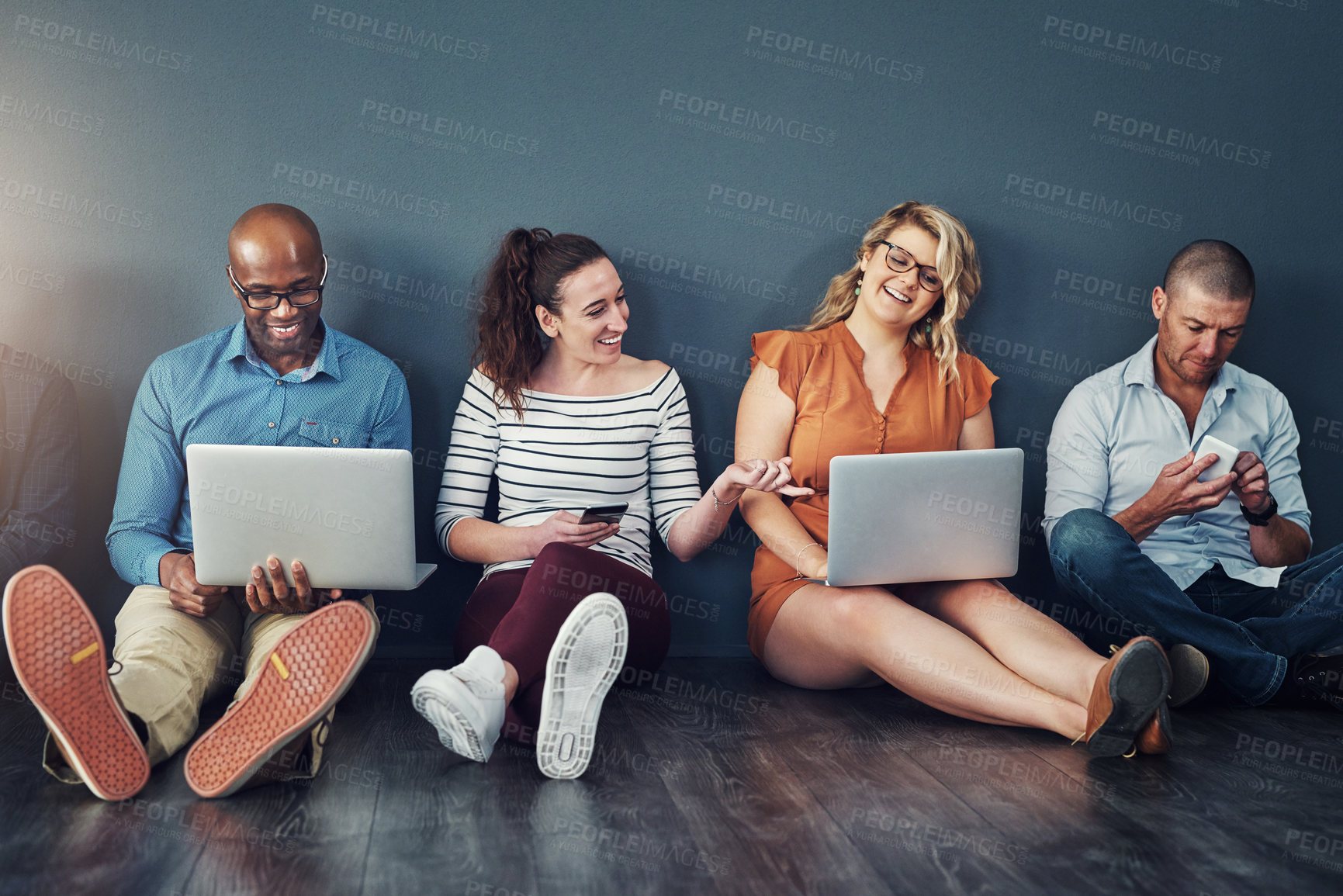 Buy stock photo Diverse modern group of business people sitting on social media networking apps on their digital devices. creative team of work colleagues connected online with laptop pcs and phones 