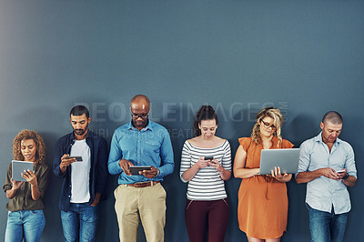 Buy stock photo A group of people distracted due to the overuse of technology against gray studio background. Many employees are addicted and obsessed with social media with a dependence on gadgets or devices