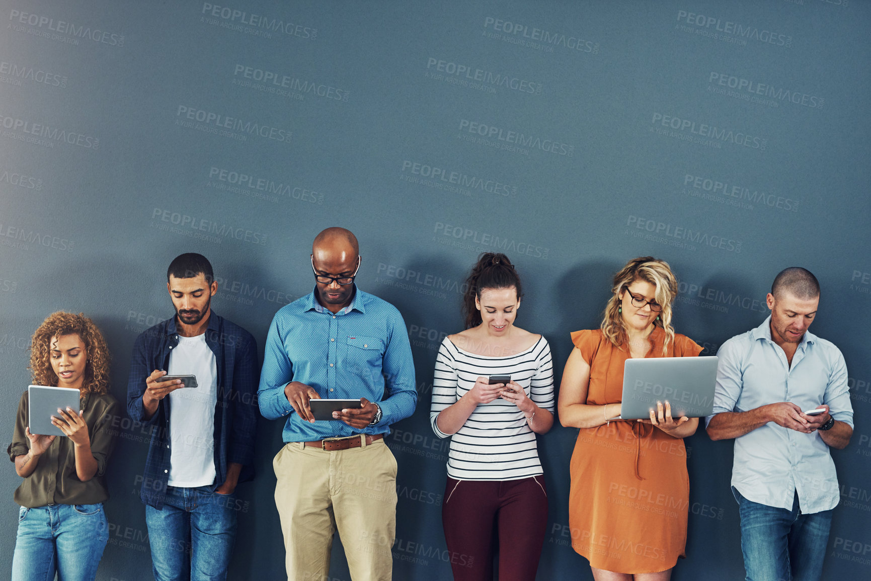 Buy stock photo A group of people distracted due to the overuse of technology against gray studio background. Many employees are addicted and obsessed with social media with a dependence on gadgets or devices