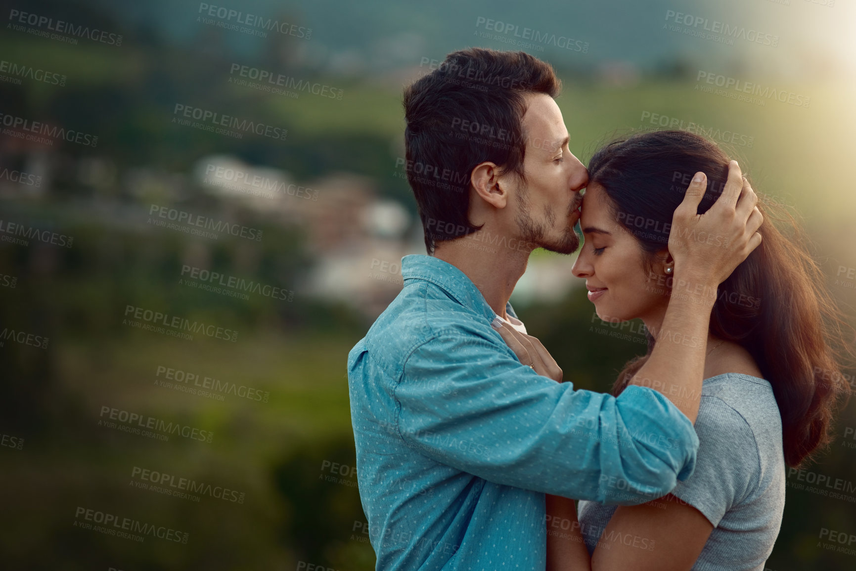 Buy stock photo Cropped shot of an affectionate young couple sharing a loving moment while standing outdoors