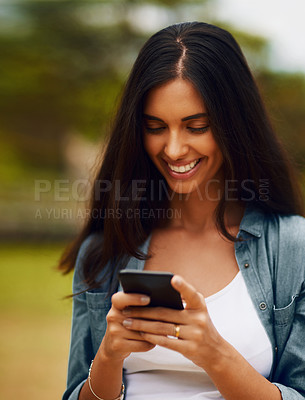 Buy stock photo Shot of an attractive young woman using a mobile phone in a park