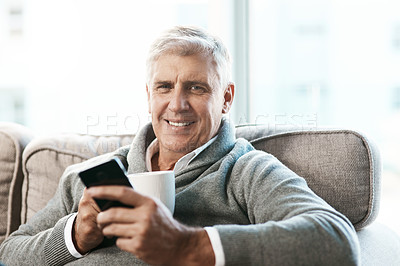 Buy stock photo Cropped portrait of a handsome mature man enjoying a coffee while reading a text on the sofa at home
