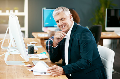 Buy stock photo Cropped portrait of a handsome mature businessman looking over paperwork while working in his office