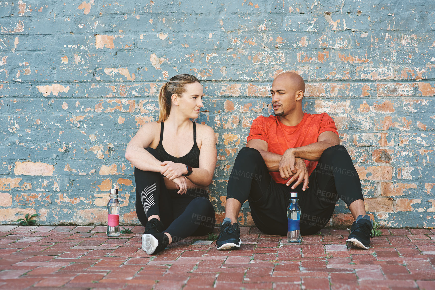Buy stock photo Break, fitness and coach with woman for workout, exercise and water bottle for sport. Partnership, personal trainer and athlete on tired by brick wall at gym for wellness, training and health