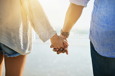 Buy stock photo Couple, relax and holding hands on beach for travel, bonding and holiday with sunshine, love and support. Man, woman and together outdoor by ocean for vacation, back and summer with romantic date