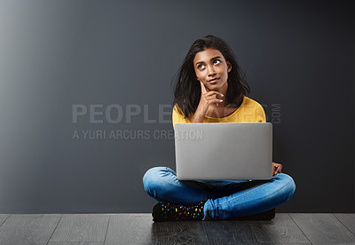 Buy stock photo Studio shot of an attractive young woman using a laptop against a gray background