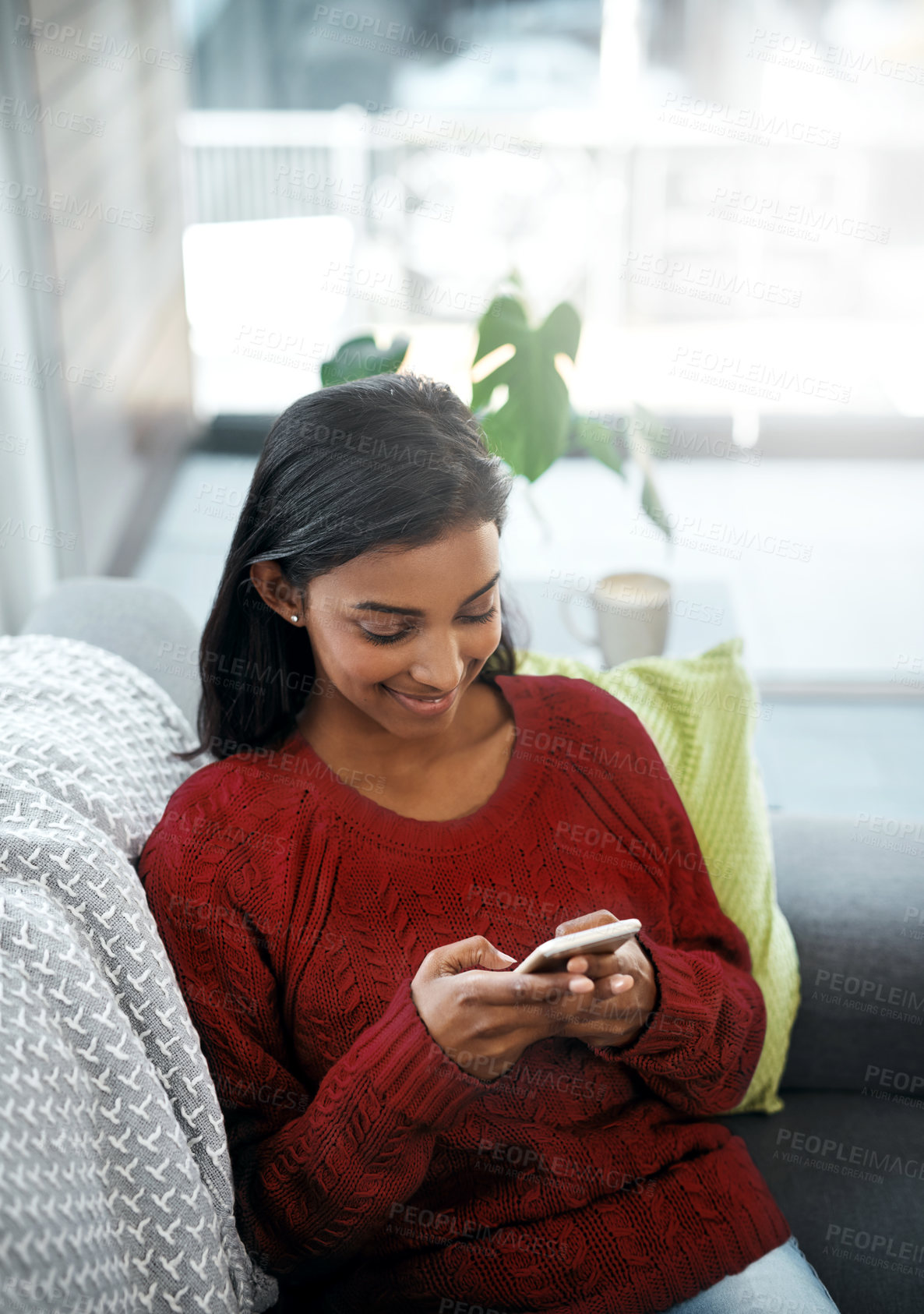 Buy stock photo Relax, smile and Indian woman on sofa with phone for social media, networking or streaming on weekend. Happy, scroll and girl on couch on smartphone for communication, online chat or search in lounge