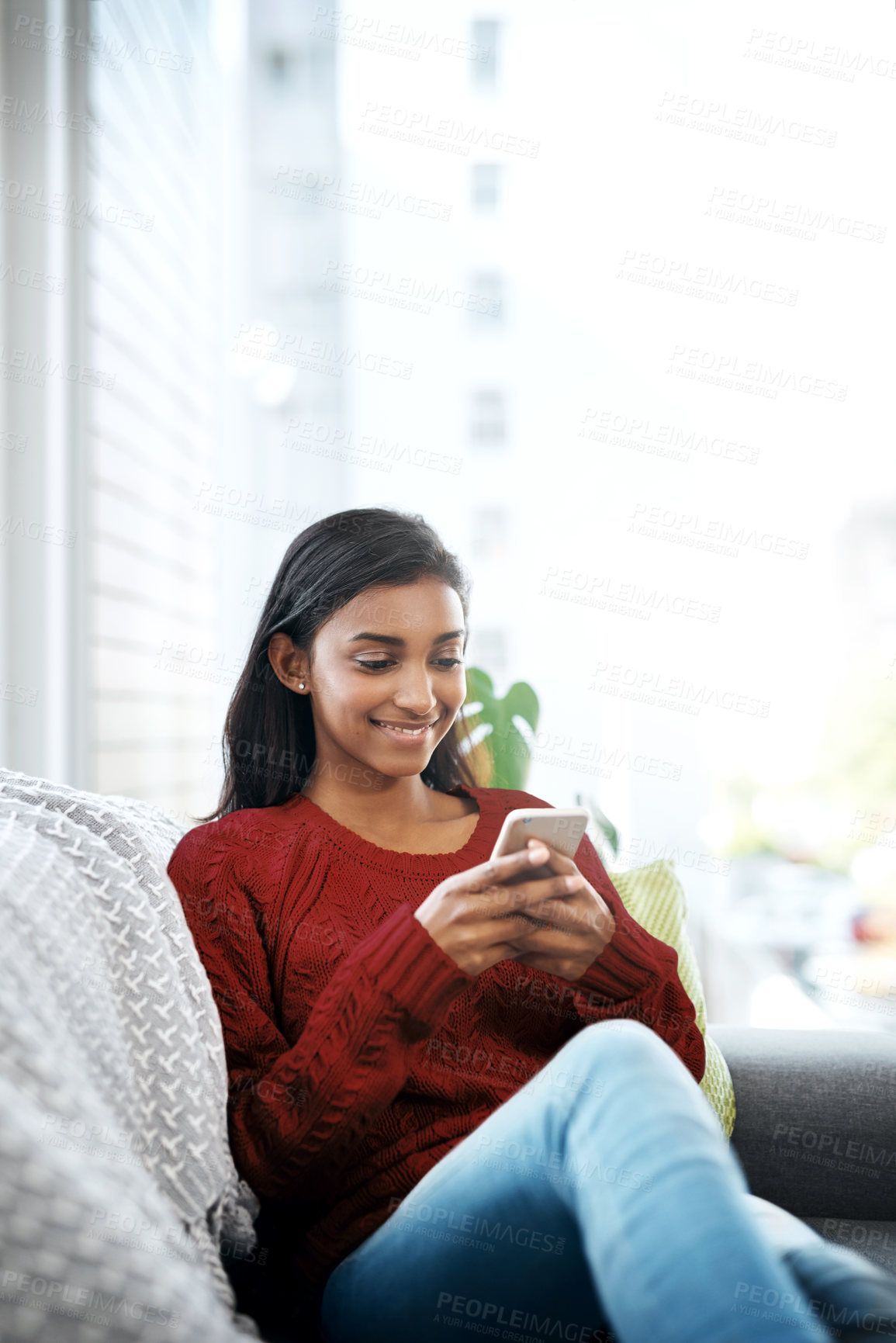 Buy stock photo Relax, smile and Indian woman on couch with phone for social media, networking or reading on weekend. Happy, scroll and girl on sofa with smartphone for communication, online chat or search in home