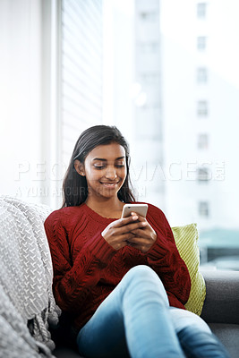 Buy stock photo Relax, smile and Indian woman on sofa with smartphone for social media, networking or streaming on weekend. Happy, scroll and girl on couch on phone for communication, online chat or search in home