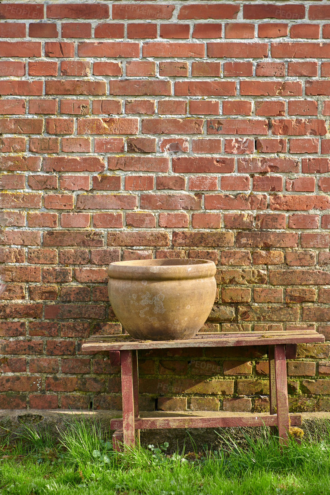 Buy stock photo Table, pot and outdoor at brick wall with grass, aesthetic and garden design with creativity. Ceramics, plants and wood at house backyard for landscaping, decoration and home improvement with space