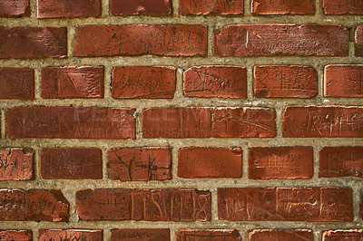 Buy stock photo Closeup of an old red brick wall with carvings and copyspace. Zoom in on different size, shape and patterns of bricks. Details of built structure with rough surface, sketched or scratched markings 