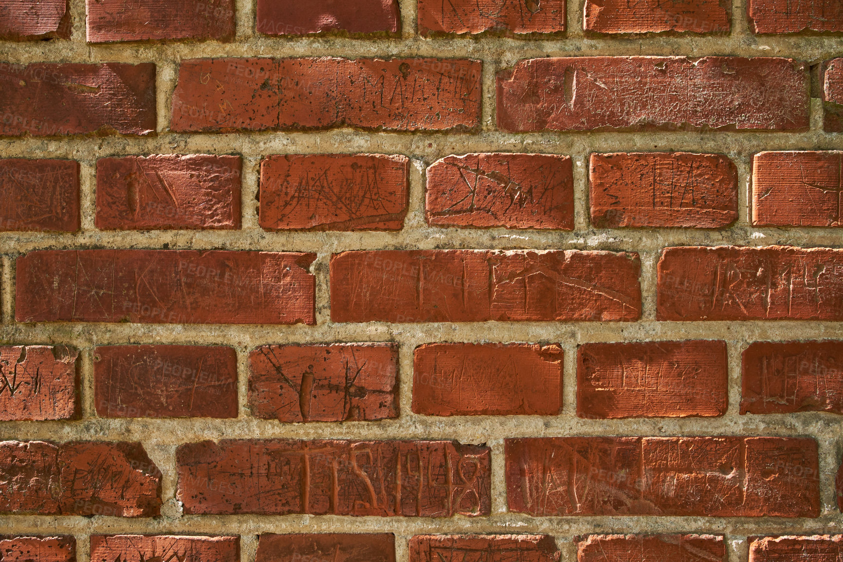 Buy stock photo Closeup of an old red brick wall with carvings and copyspace. Zoom in on different size, shape and patterns of bricks. Details of built structure with rough surface, sketched or scratched markings 