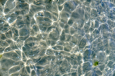 Buy stock photo Clear beach water on a summer day with copy space. Top view of calm low tide sea ripples during spring. Closeup of the bright sun reflection shining off the shallow ocean useful as a background