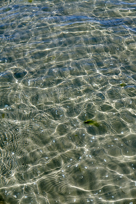 Buy stock photo A clear water surface on the sea coast with the seashell and wavy water on a sunny day. The top view of transparent sea water at the seashore with the reflection of scattered sunlight under the water