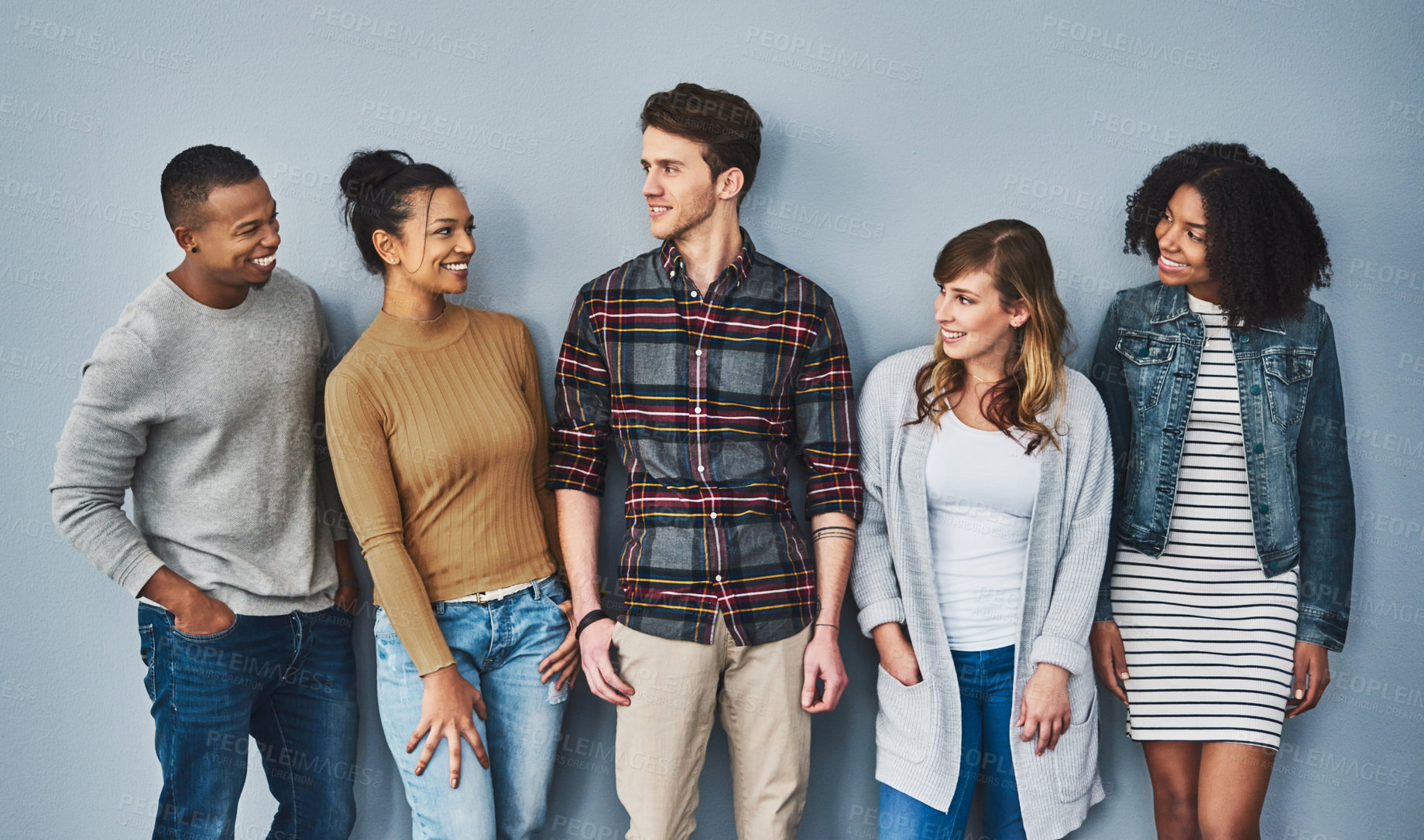 Buy stock photo Studio shot of a diverse group of young people standing together against a gray background